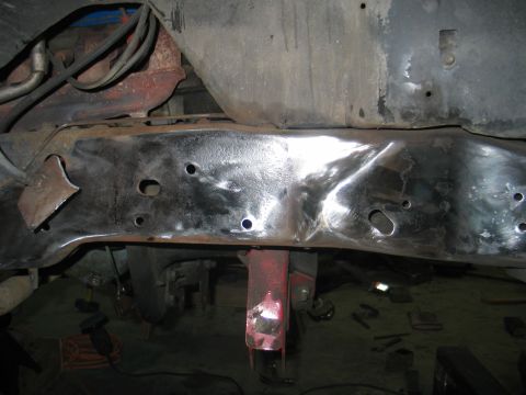 1984 Ford Bronco - Underside view of a vehicle's frame and suspension, with a red jack supporting the chassis.