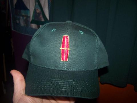 1987 Lincoln Mark VII - A green baseball cap displays the Lincoln logo, held in a person's hand.