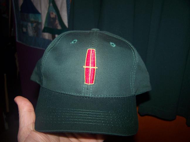 Green baseball cap with red Lincoln logo held by a hand