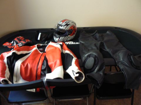 1978 Ford Bronco - Motorcycle riding gear including a jacket, pants, helmet, and gloves are arranged on chairs.