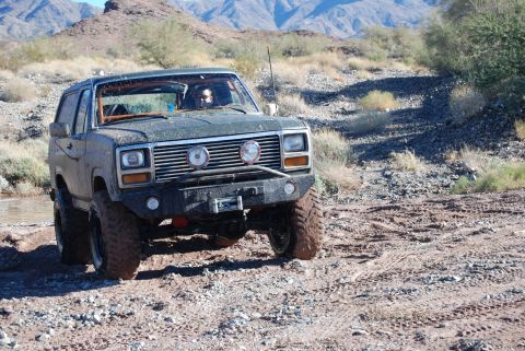 1982 Ford Bronco - This modified SUV navigates a challenging off-road course in a desert landscape.