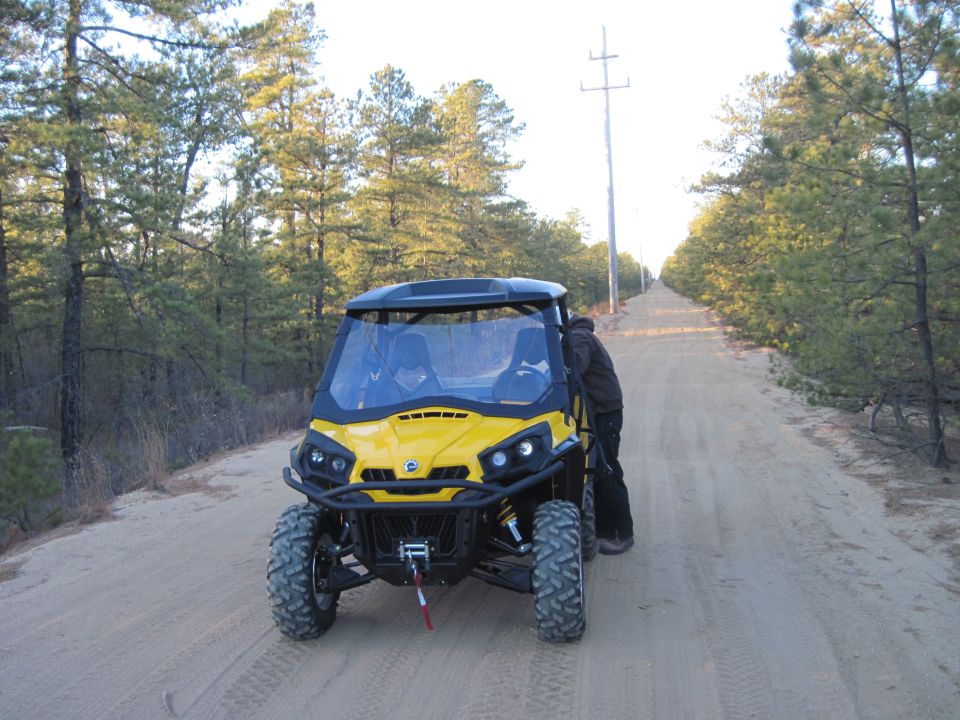 Yellow Can-Am Commander side-by-side UTV with a winch on a dirt road