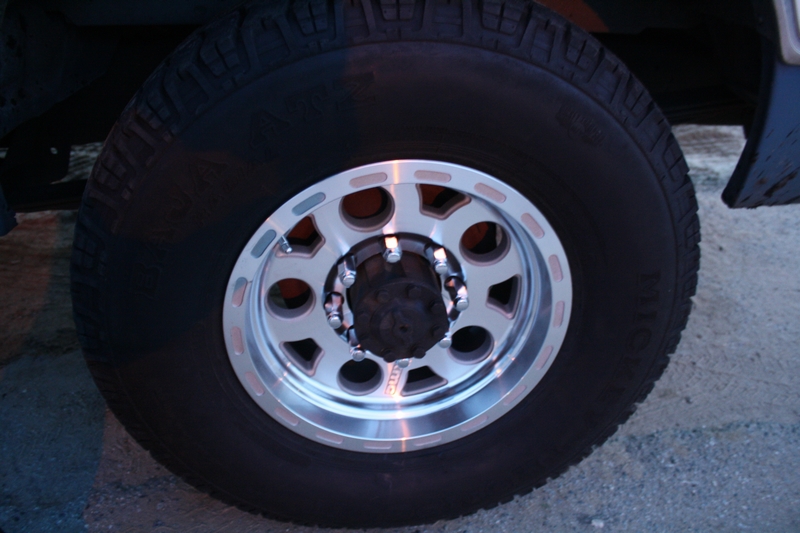 Polished 8-lug aluminum wheel with Michelin all-terrain tire, close-up