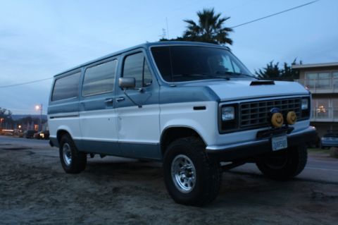 1989 Ford Bronco - This van has a two-tone paint job and is equipped with off-road tires and custom bumper lights.
