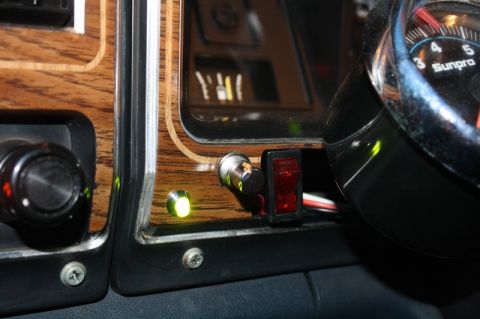 1989 Ford Bronco - Close-up of a vehicle's interior dashboard, wood grain trim, aftermarket switches, and a Sunpro gauge.
