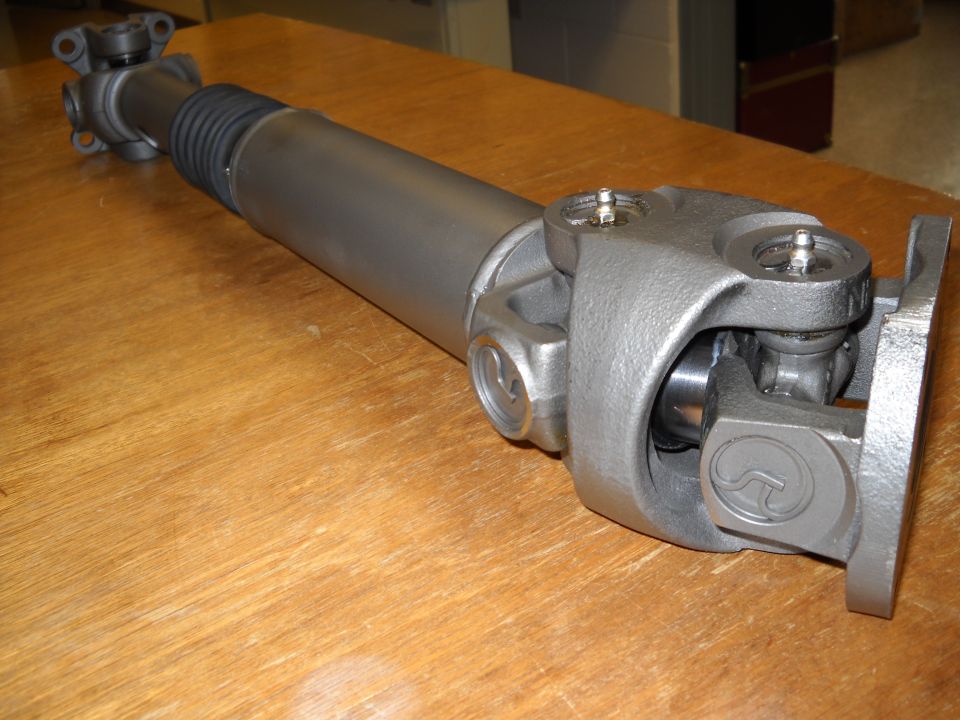 Driveshaft with double-cardan CV joint and flange yoke resting on a wood bench