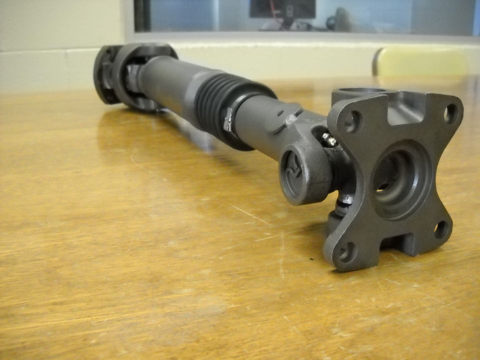 Short double-cardan driveshaft with flange yoke on a wood workbench