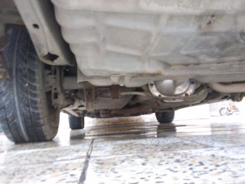 1998 Ford Crown Victoria - The underside of a car is viewed from below, revealing mechanical components and a tire.