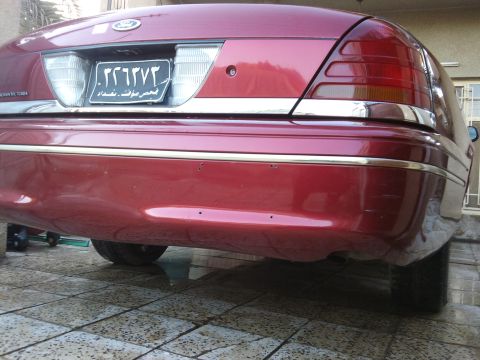 1998 Ford Crown Victoria - Rear view of a red 1998 Ford Crown Victoria, showing its distinctive taillights and chrome bumper accents.