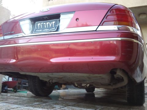 1998 Ford Crown Victoria - Rear view of a red 1998 Ford Crown Victoria, showing the bumper, taillights, and exhaust system.