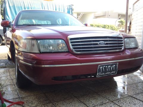 1998 Ford Crown Victoria - Front view of a red 1998 Ford Crown Victoria with a chrome grille and a license plate.