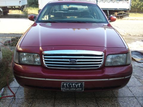 1998 Ford Crown Victoria - Front view of a red 1998 Ford Crown Victoria, showing its distinctive grille and headlights.
