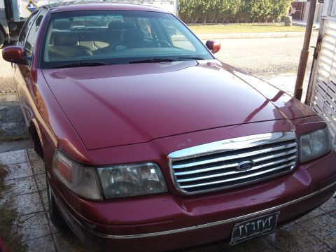1998 Ford Crown Victoria - Front view of a maroon Ford Crown Victoria parked outdoors. The grille and headlights are clearly visible.