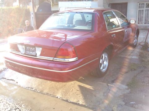 1998 Ford Crown Victoria - Rear view of a red 1998 Ford Crown Victoria sedan with chrome accents and alloy wheels.