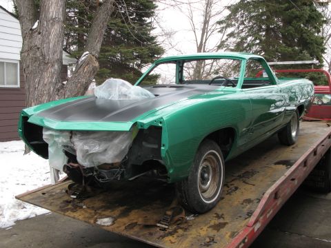 1971 Ford Ranchero - Green 1971 Ford Ranchero project car being transported on a flatbed trailer.