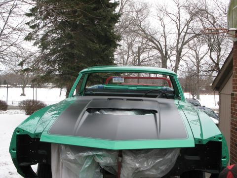 1971 Ford Ranchero - A partially disassembled green vehicle with a black hood sits outside in the snow.