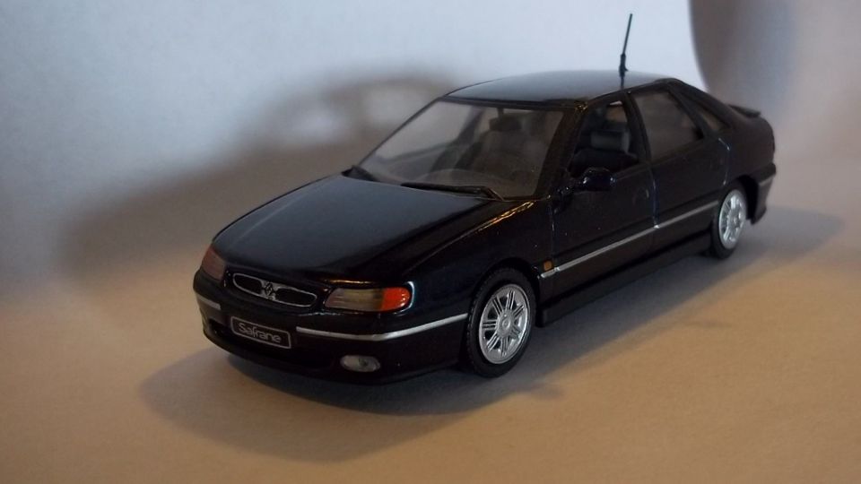 Black Renault Safrane scale model sedan, front three-quarter view on tan surface