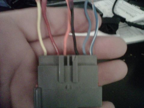 1993 Ford Bronco - A hand holds a gray wiring harness connector with several colored wires, suggesting a vehicle repair or modification.