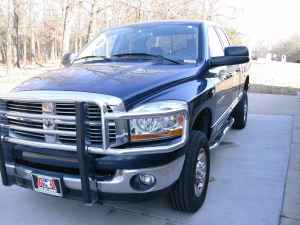 2006 Dodge 2500 - Front 3/4 view of a blue Dodge pickup truck with a chrome grille guard. The truck is parked on a concrete surface outdoors.