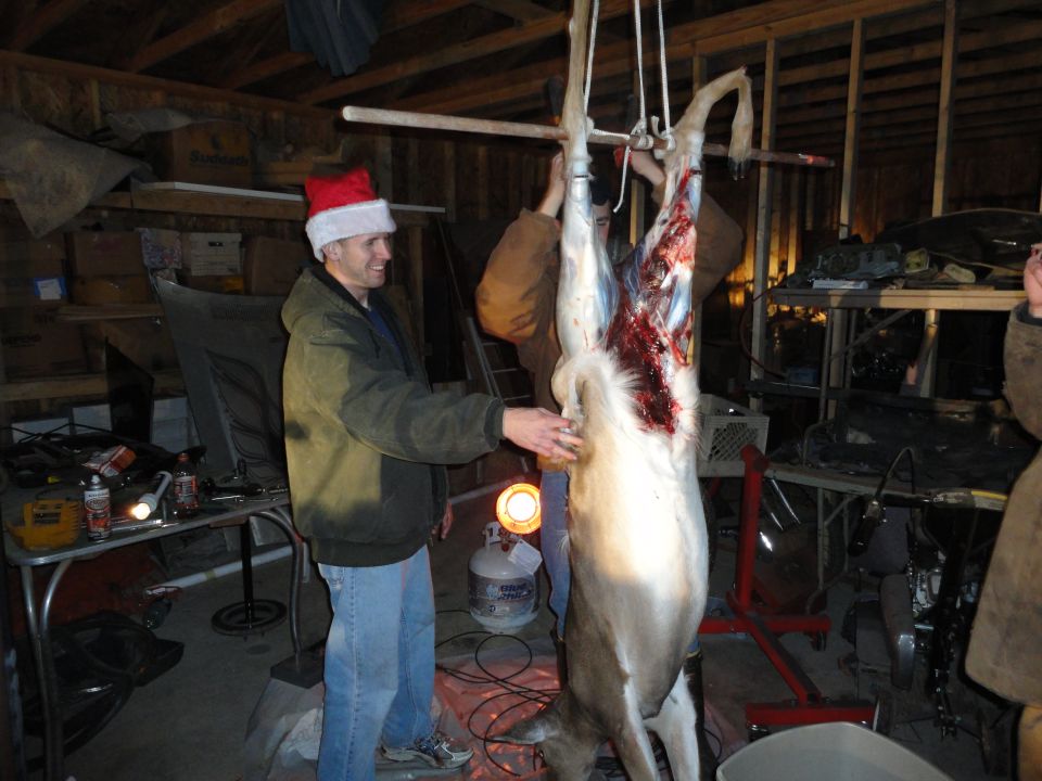 guy in santa hat next to hanging deer in garage
