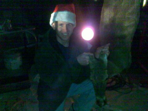 2006 Dodge 2500 - A man in a Santa hat poses with a deer leg, illuminated by a bright light.
