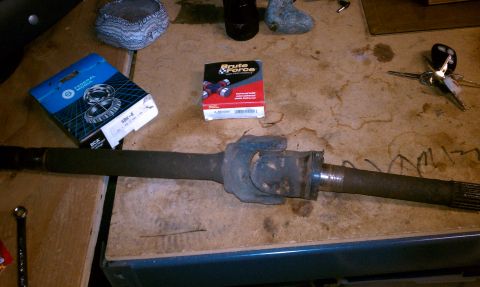1994 Ford F-150 - A driveshaft and parts are laid out on a workbench, possibly for a vehicle repair or rebuild.