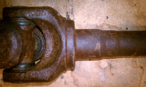 1994 Ford F-150 - Close-up of a rusty driveshaft universal joint, showing some stamped part numbers on the yoke.