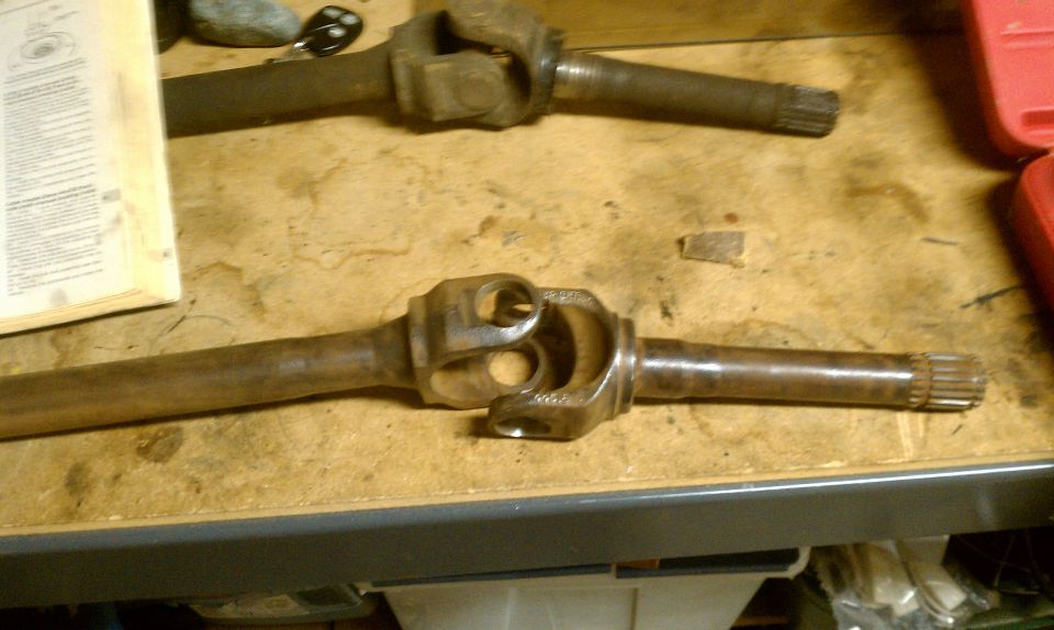 Two driveshafts with U-joints on a workbench