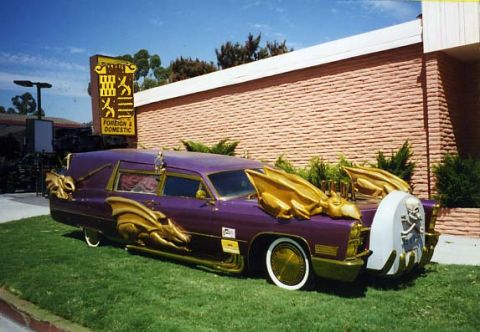 1991 Ford LTD Crown Victoria - A custom purple hearse is parked on a grassy lawn in front of a brick building, adorned with gold dragon motifs.