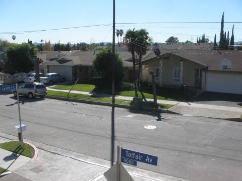1968 Ford Mustang - Residential street scene with houses and parked vehicles under a clear blue sky.