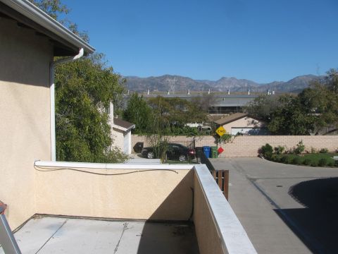 1968 Ford Mustang - A black sedan is parked in a driveway with a residential building and mountains in the background.