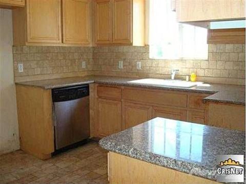 1968 Ford Mustang - This kitchen features granite countertops, light wood cabinets, and a stainless steel dishwasher, with a large sink area visible.