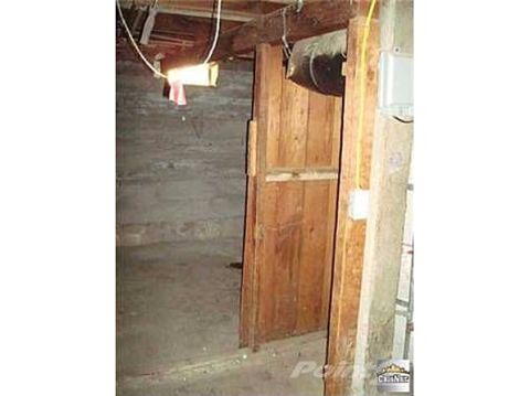 1968 Ford Mustang - Basement interior shows concrete walls, a wooden door, and exposed ceiling structure with utilities.