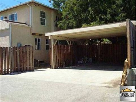 1968 Ford Mustang - A covered carport is attached to a residential building, with a wooden fence in the foreground.
