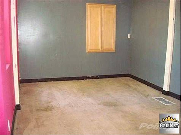 Interior room with pink wall, grey walls, and wooden cabinets above a window