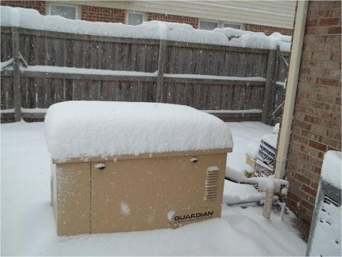 1972 Ford Ranchero - A generator sits covered in snow in a backyard setting, with a wooden fence and brick wall visible.