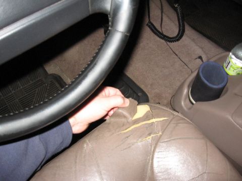 1995 Ford Bronco - A hand pulls at a ripped car seat, revealing yellow foam underneath.