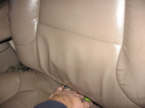 1995 Ford Bronco - Close-up view of tan perforated leather seats, with a hand reaching into the gap between them.