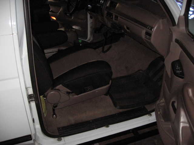 Interior of truck/SUV through open driver's door showing tan and black seat and floor