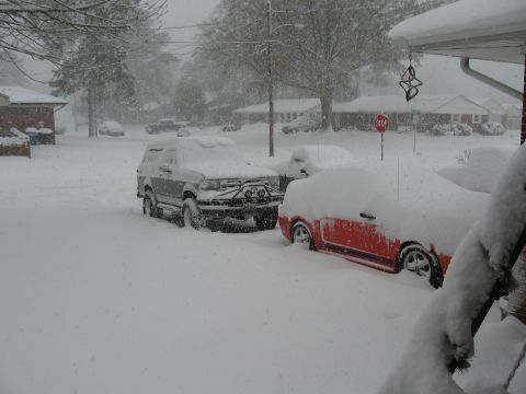 1994 Ford Bronco - A gray Ford Bronco and a red car are buried in snow during a winter storm.