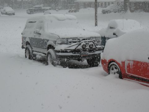 1994 Ford Bronco - A 1994 Ford Bronco is partially buried in snow, a custom front bumper with auxiliary lights.