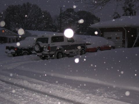 1994 Ford Bronco - Ford Bronco covered in snow, parked next to another car in a driveway during a winter storm.