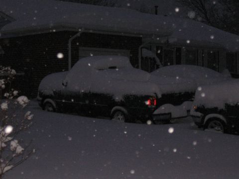 1994 Ford Bronco - Several vehicles are buried under a thick blanket of snow as it continues to fall.