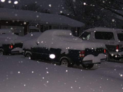 1994 Ford Bronco - Multiple vehicles are covered in snow during a heavy snowfall at night.