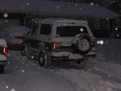 1994 Ford Bronco - A 1994 Ford Bronco is seen from the rear, covered in snow during a winter storm.