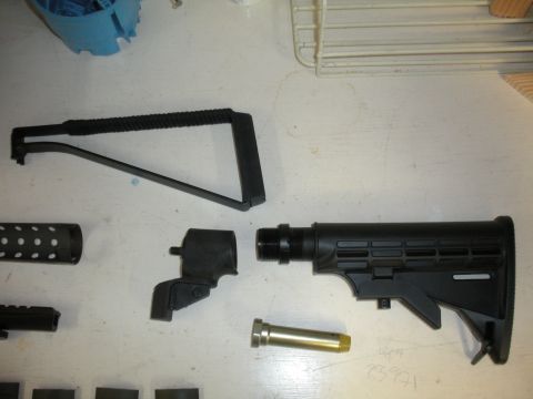 1996 Ford Bronco - Firearm components are laid out on a white surface, including a stock, buffer tube, and a perforated barrel shroud.