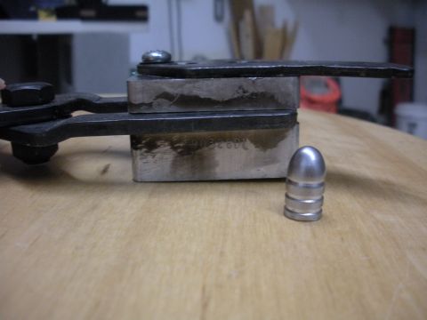 1996 Ford Bronco - Close-up of a bullet mold and a single bullet on a wooden surface.