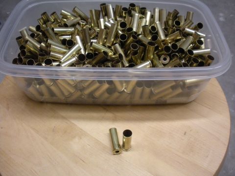 1996 Ford Bronco - Container of brass shell casings with two loose casings on a wooden surface.