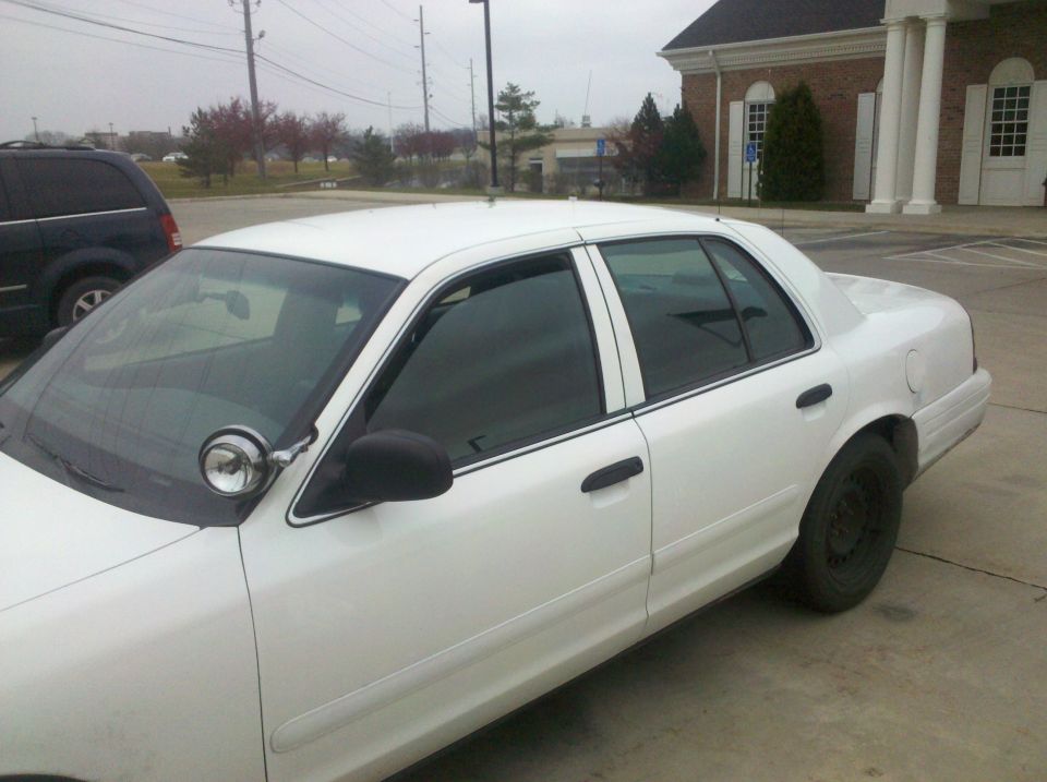 White 2001 Ford Crown Victoria, side view, with a spotlight mounted on the driver's side fender