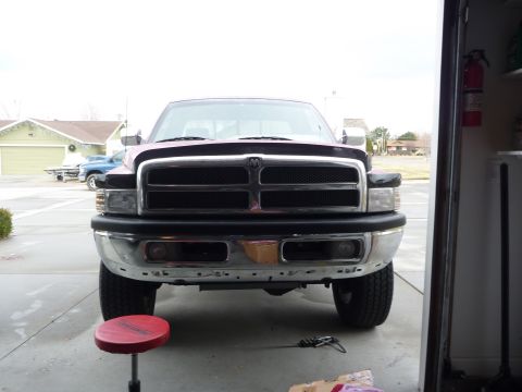 1997 Dodge 2500 - A Dodge Ram pickup truck is viewed from the front, parked outside a garage with a red stool nearby.